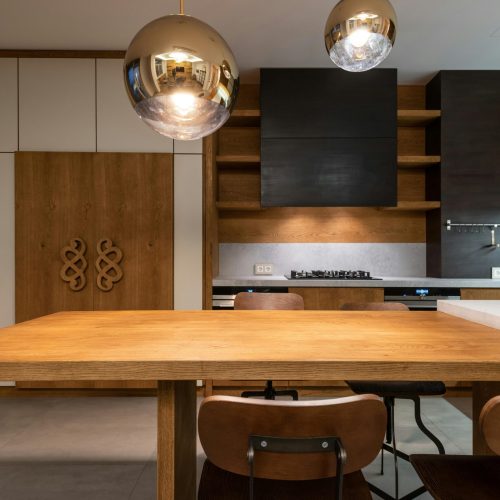Sleek minimalist kitchen with wooden cabinetry and modern pendant lights.